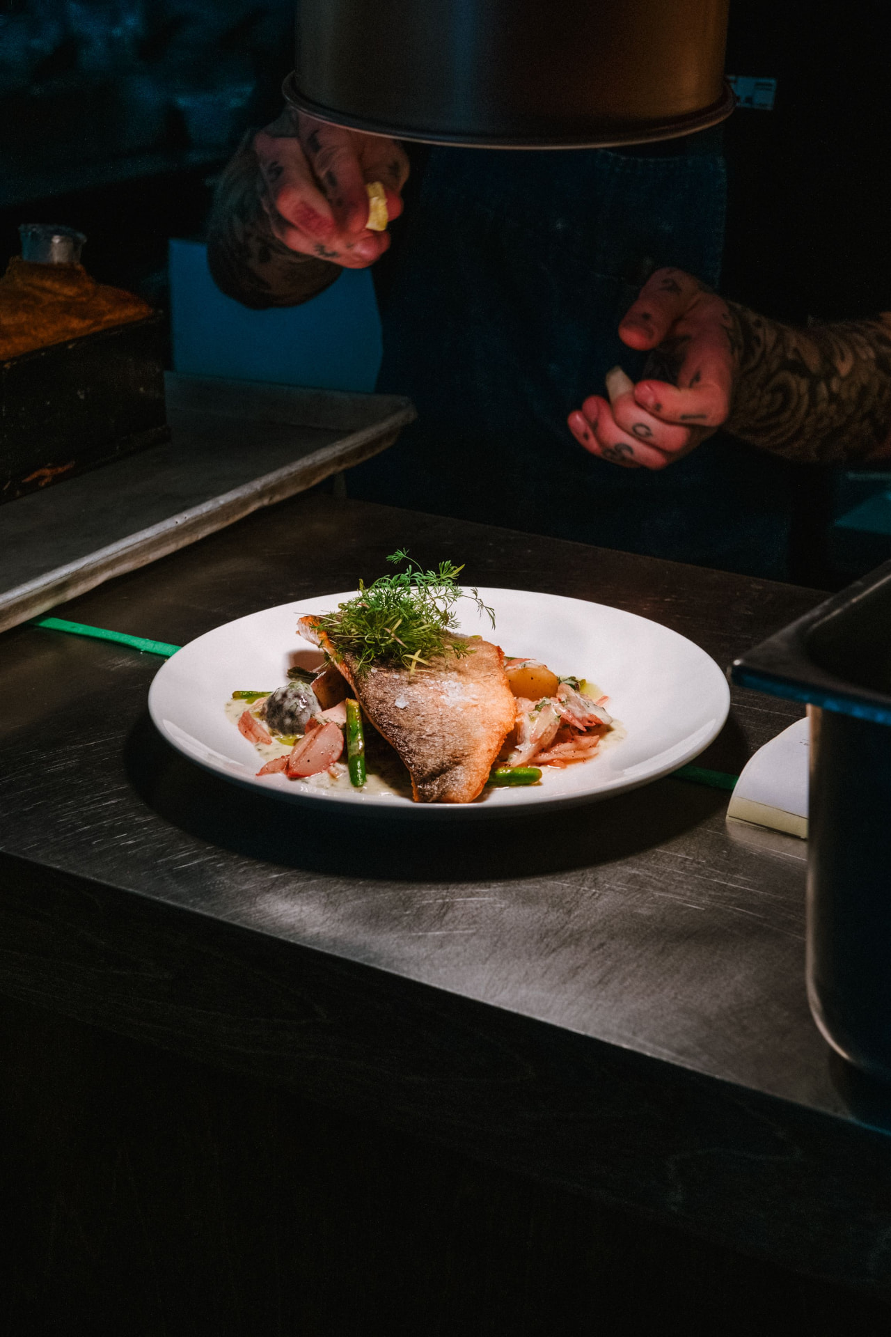 Chef finishing a plated fish dish
